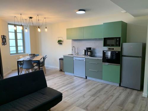 een keuken met groene kasten en een tafel en een bank bij Appartement Torii - Maulévrier Cholet Puy du Fou in Maulévrier