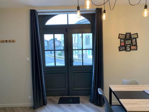 een deur met een raam in een kamer met een tafel bij Appartement Torii - Maulévrier Cholet Puy du Fou in Maulévrier
