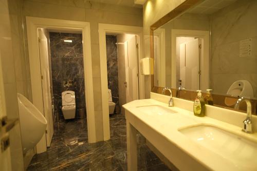 a bathroom with two sinks and a toilet and a mirror at Malabadi Hotel in Diyarbakır