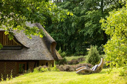 a thatch roofed house with a bench in the yard at Stimbekhof in Bispingen