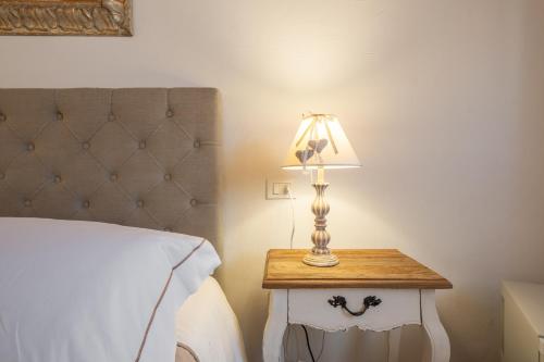 a lamp on a side table next to a bed at Dimoras Dimore Esclusive in Olbia