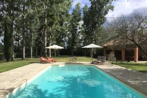 une piscine avec chaises et parasols dans une cour dans l'établissement Lobersane La Maison du meunier, à Saint-Laurent