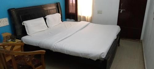 1 dormitorio con 1 cama grande con sábanas y almohadas blancas en Hotel tara inn, en Jaunpur
