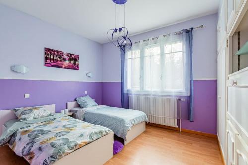 a bedroom with two beds and purple walls at Charmante Maison au calme in Yerres