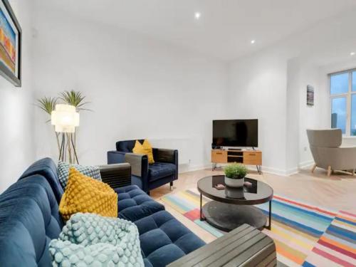 a living room with a blue couch and a table at Pass the Keys Golfers Haven 2 BD Flat on Hoylake Beach Parking in Hoylake