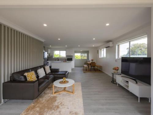 a living room with a black couch and a tv at Convenient Comfort 4BR near Malls and Transport in Brisbane