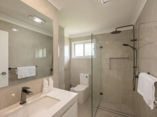 a bathroom with a shower and a sink and a toilet at Convenient Comfort 4BR near Malls and Transport in Brisbane