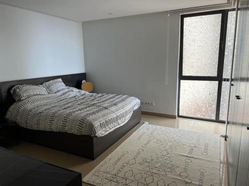 a bedroom with a bed and a window and a rug at Bel Appartement en face de la mer in Dakar