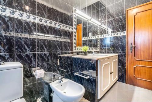ein schwarz gefliestes Badezimmer mit Toilette und Waschbecken in der Unterkunft Villa Paraíso in Poço Partido