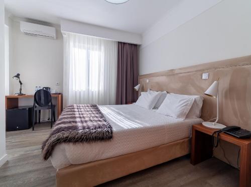 a hotel room with a large bed and a desk at Hotel Porto Mar in Matosinhos