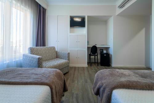 a hotel room with two beds and a chair at Hotel Porto Mar in Matosinhos