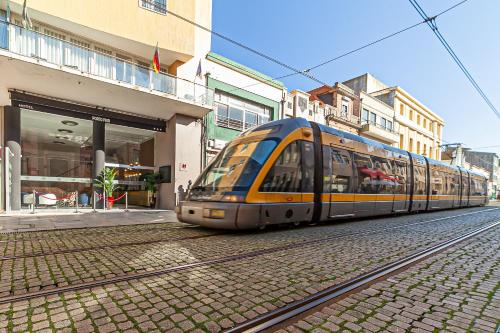 a train on the tracks next to a building at Hotel Porto Mar in Matosinhos