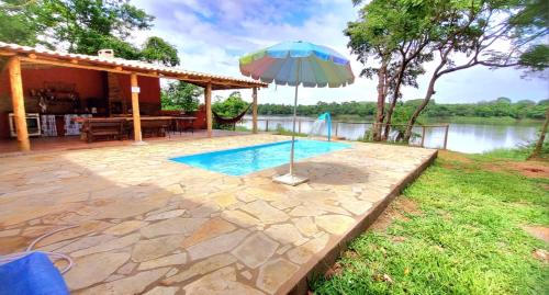 een zwembad met een parasol naast een huis bij Rancho Sagarana in Três Marias