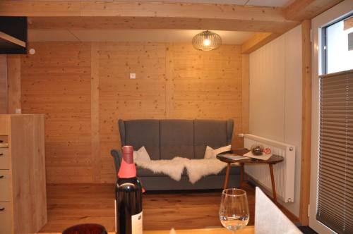 a room with a couch and a table with a bottle of wine at Hotel Maroi in Wald am Arlberg