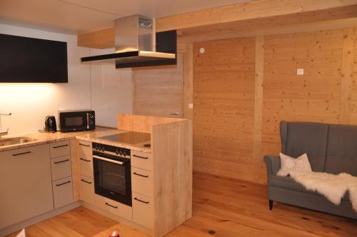 a kitchen with a stove top oven next to a couch at Hotel Maroi in Wald am Arlberg