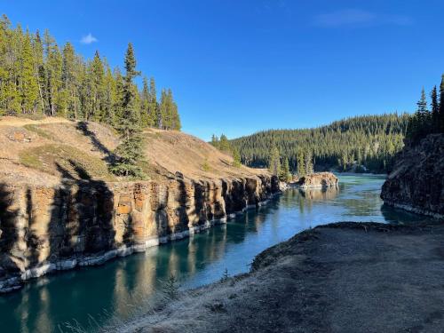 a river with rocks and trees in the background at Elite Hotel "Downtown Center" " Ski & Northern light Tour" in Whitehorse