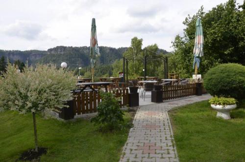 a patio with tables and umbrellas in a garden at Penzion u Marešů in Hřensko