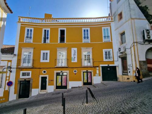 a yellow building with white windows on a street at Very Typical - Alojamento Local in Elvas