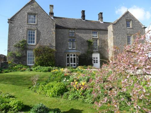 an old stone house with a garden in front of it at Stanshope Hall in Alstonfield