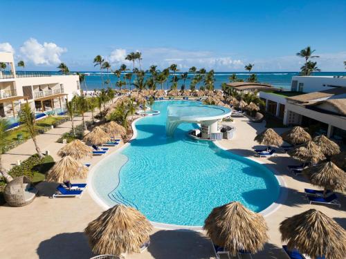 a swimming pool with straw umbrellas and the ocean at Serenade All Suites - Adults Only Resort in Punta Cana