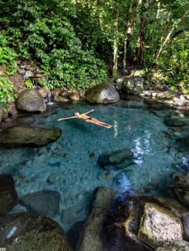 a pool of blue water with rocks and trees at Cabañita La Montaña de Las Brisas in San Vito