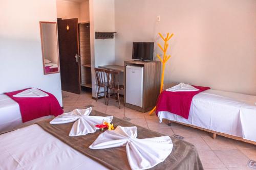 a hotel room with two beds and a table at Ferrujão Pousada e Restaurante in Garopaba