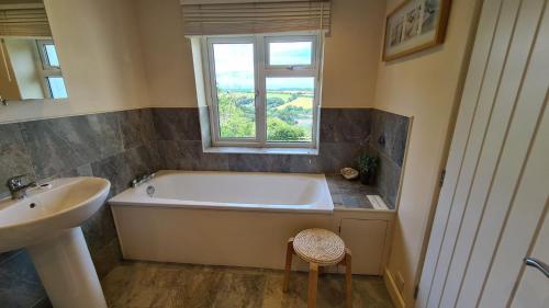 a bathroom with a tub and a sink and a window at Tantallon in Saint Just in Roseland