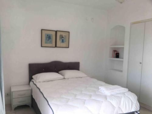 a white bed in a white bedroom with two pictures on the wall at Castle81homes Blue - Sea view house in Marmaris