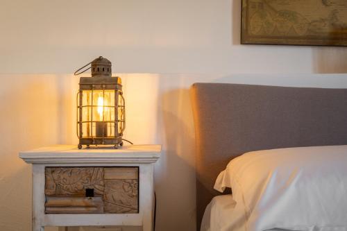 a lamp on a night stand next to a bed at Dimoras Dimore Esclusive in Olbia