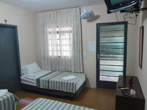 Schlafzimmer mit einem Bett, einem Spiegel und einem Fenster in der Unterkunft POUSADA MONTE HOREB in Cachoeira Paulista