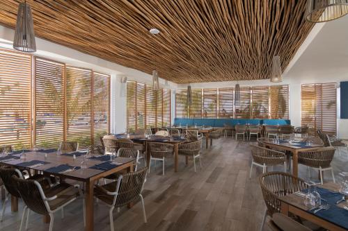 a dining room with tables and chairs and windows at Serenade All Suites - Adults Only Resort in Punta Cana