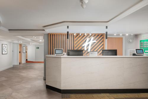 a lobby with a reception desk and a counter at Holiday Inn Northampton, an IHG Hotel in Northampton