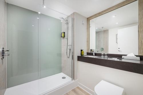 a bathroom with a glass shower and a sink at Holiday Inn Northampton by IHG in Northampton
