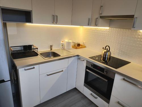 a small kitchen with white cabinets and a sink at Apartament Optymalny in Tczew
