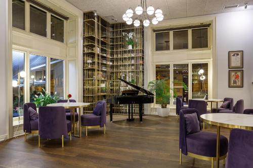 a room with tables and chairs and a piano at Modern Art Hotel in Lviv