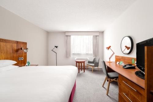 a hotel room with a bed and a desk and a table at Holiday Inn Northampton by IHG in Northampton