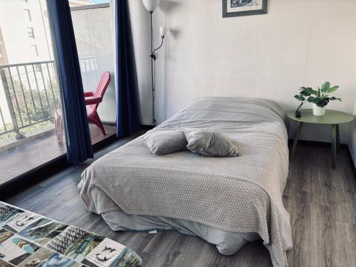 a bedroom with a bed and a table and a window at Superbe studio pour 2 à 20m de la plage - 27 in Canet-en-Roussillon
