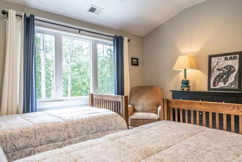 sypialnia z 2 łóżkami, krzesłem i oknem w obiekcie Sleeps 10 Whispering Pines 