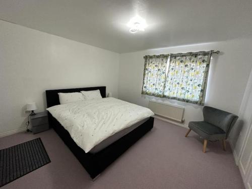 a bedroom with a bed and a chair and a window at Spacious & Lovely 4 Bedroom Home in Manchester in Manchester