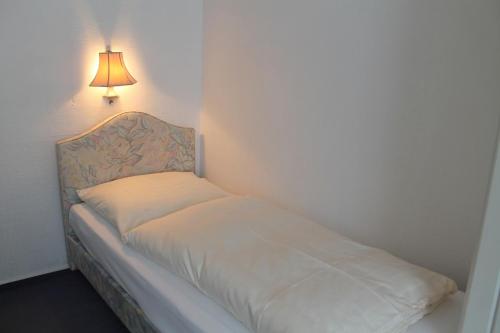 a small bed in a room with a lamp at Centro Hotel Arde Köln City, Trademark Collection by Wyndham in Cologne