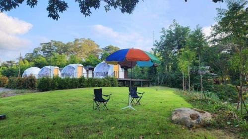 a table and two chairs under an umbrella in a yard at Riverhill khaoyai Camping in Pong Talong
