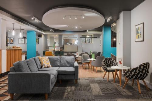 a living room with a couch and tables and chairs at Holiday Inn Northampton, an IHG Hotel in Northampton