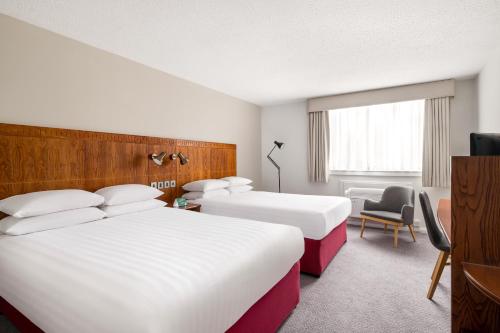 a hotel room with two beds and a chair at Holiday Inn Northampton by IHG in Northampton