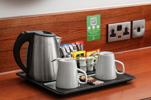 a tea kettle and cups on a tray on a counter at Holiday Inn Northampton by IHG in Northampton