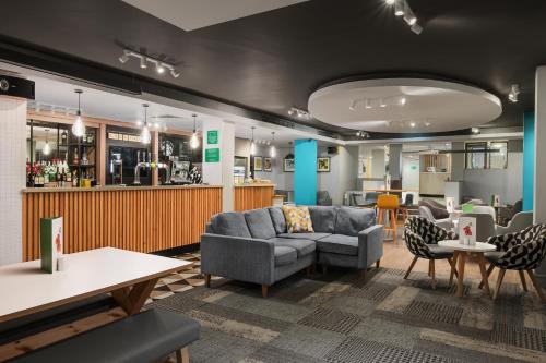 a lobby with a couch and chairs and a bar at Holiday Inn Northampton by IHG in Northampton