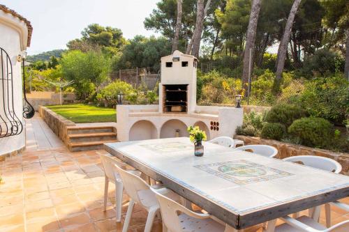a patio with a table and chairs and a grill at Villa La Paz in El Tosalet