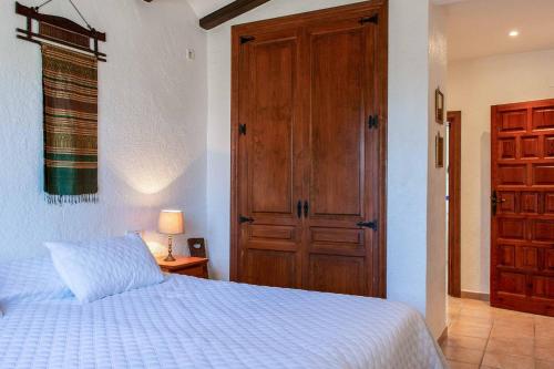 a bedroom with a white bed and a wooden door at Villa La Paz in El Tosalet