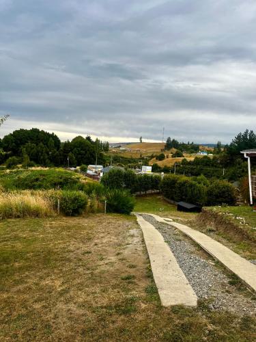a path in a field with trees and a house at Espectacular Cabaña en Castro in Castro