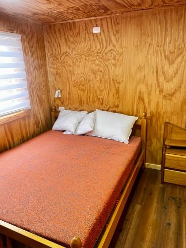 a bed in a room with a wooden wall at Espectacular Cabaña en Castro in Castro