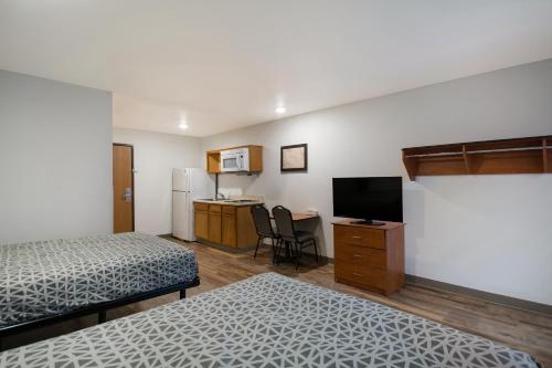 a room with two beds and a kitchen with a television at WoodSpring Suites Macon West I-475 in Macon